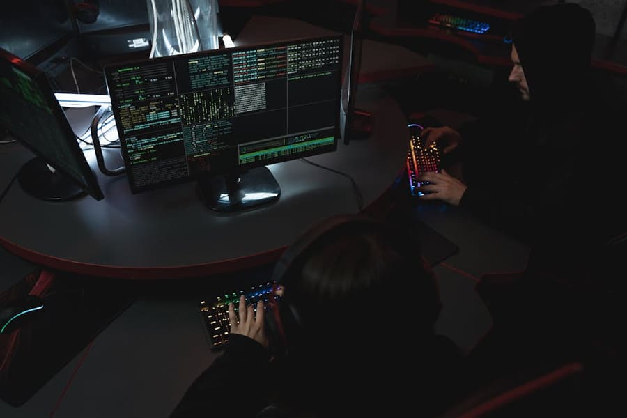A group of people in a dark room working on computers, related to cybersecurity.
